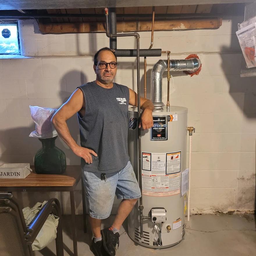 Ron of Ron’s Plumbing, Heating and Air Conditioning next to a finished Bradford White water heater installation